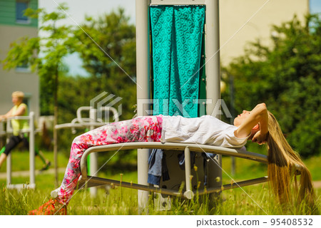 Girl doing situps in outdoor gym Girl doing situps in outdoor gym 95408532