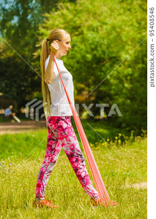 Girl doing exercises outdoor, using resistance fit band. 95408546