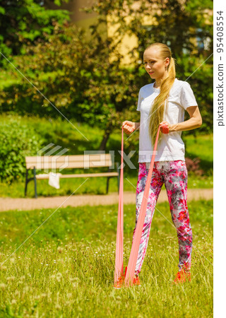 Girl doing exercises outdoor, using resistance fit band. Girl doing exercises outdoor, using resistance fit band. 95408554