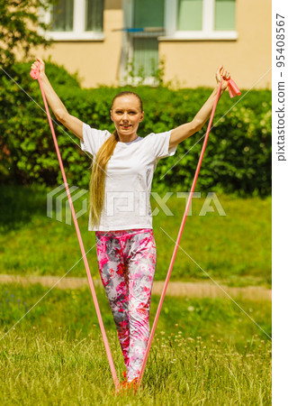 Girl doing exercises outdoor, using resistance fit band. 95408567