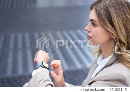 Confident businesswoman with digital watch, going on a meeting, checking messages or time, wearing office suit Confident businesswoman with digital watch, going on a meeting, checking messages or time, wearing office suit 95409145