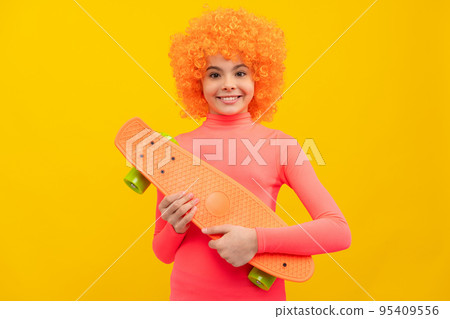 Happy girl scater with orange hair in pink poloneck smile holding pennyboard, skateboarding 95409556