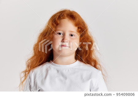 Cute little girl, kid with long curly red hair looking at camera isolated over white background. Concept of children positive emotions, beauty Cute little girl, kid with long curly red hair looking at camera isolated over white background. Concept of children positive emotions, beauty 95409806