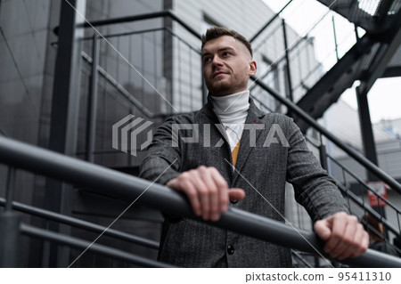 brutal portrait of a middle-aged man on a gray metal staircase near a modern building brutal portrait of a middle-aged man on a gray metal staircase near a modern building 95411310