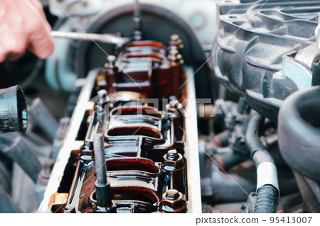 Car repair. The use of poor quality oil in the engine. Deposits of tar from oil on the inside of the engine. The mechanic examines the head on the internal combustion engine 95413007