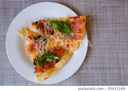 Appetizing delicious pizza. Close-up top view of slices of pizza on a white plate. Place for text. 95413169