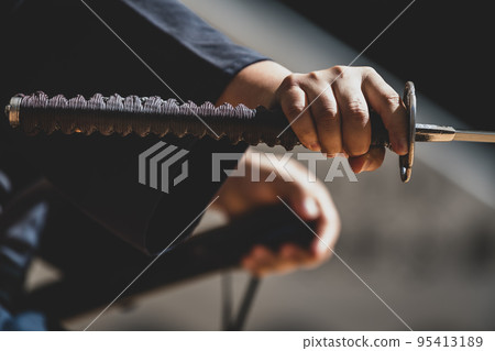 A person holding a Japanese sword A person holding a Japanese sword 95413189