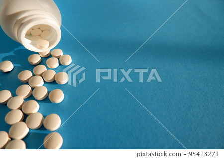 Medicine and healthcare concept. Capsules, tablets scattered near containers on a blue background. Place for your text. Medicine and healthcare concept. Capsules, tablets scattered near containers on a blue background. Place for your text. 95413271