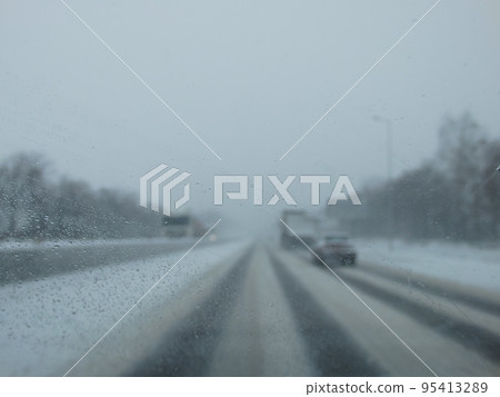 Driving in a snow storm. Poor visibility through the driver's glass onto the road covered with snow and ice. Extreme weather in winter. Winter, Blizzard. 95413289