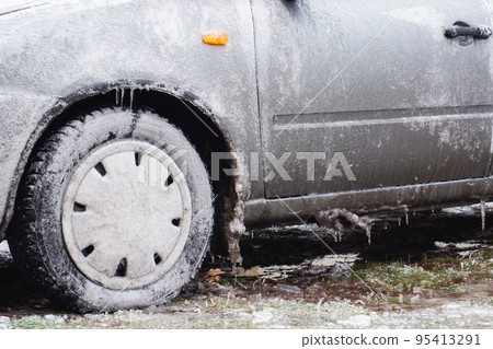 Gray passenger car covered with ice. Frozen Ice Rain. . Ice. Close-up view. 95413291
