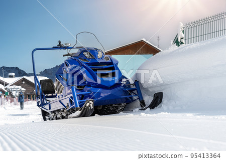 Front view big modern snow mobile scooter atv alpine mountain reosrt against sunny sky on cold snowy winter day. Snowmobile rental sport adventure trip service. Arctic nordic snow sledge transport 95413364