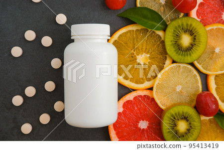 Vitamins. White empty bottle for vitamins on a background of citrus fruit slices. Pills. lemon. orange. Grey stone background. Blank Medicine bottle Vitamins. White empty bottle for vitamins on a background of citrus fruit slices. Pills. lemon. orange. Grey stone background. Blank Medicine bottle 95413419