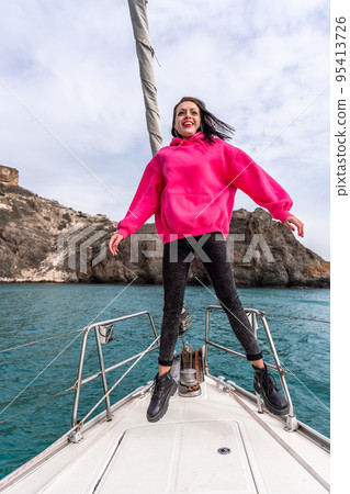 Woman standing on the nose of the yacht at a sunny summer day, breeze developing hair, beautiful sea on background Woman standing on the nose of the yacht at a sunny summer day, breeze developing hair, beautiful sea on background 95413726