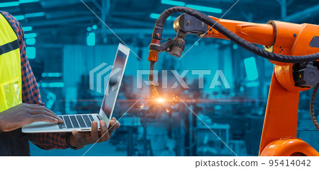 Engineer worker using laptop computer program control Robotic Arm Welding with AI automation system in advanced modern metal factory.Industry 5.0 fabrication process concept. 95414042