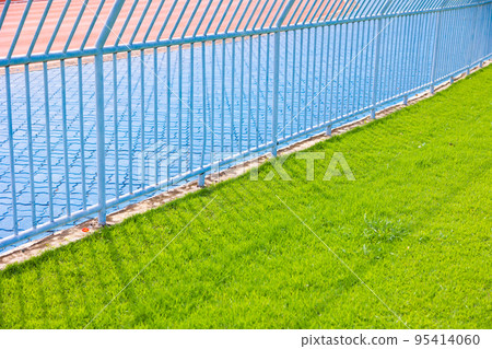 green grass around sport stadium aside running track with fence 95414060
