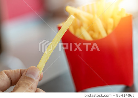 french fries. closeup male hand holding golden potato stick fry popular american fast food. french fries. closeup male hand holding golden potato stick fry popular american fast food. 95414065