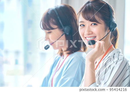 A young female operator looking at a camera working in a call center A young female operator looking at a camera working in a call center 95414216