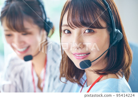 A young female operator looking at a camera working in a call center A young female operator looking at a camera working in a call center 95414224