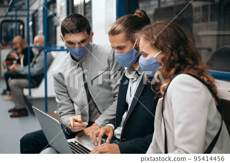 group of young people discussing online news while sitting in a subway car. group of young people discussing online news while sitting in a subway car. 95414456