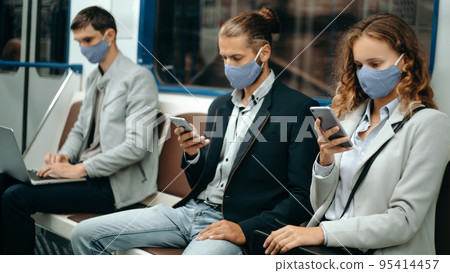 young people in protective masks sitting at a safe distance in the subway car. young people in protective masks sitting at a safe distance in the subway car. 95414457