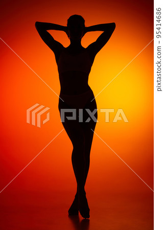 Silhouette of female full-length body isolated over orange background. Relaxation, wellness Silhouette of female full-length body isolated over orange background. Relaxation, wellness 95414686