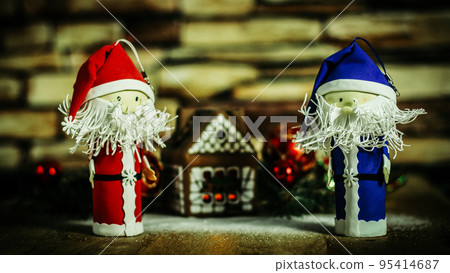 two funny Santa Claus on the background of a gingerbread house. two funny Santa Claus on the background of a gingerbread house. 95414687