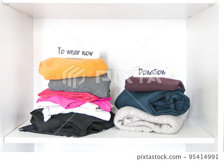 Different clothes in home wardrobe with paper notes. Small space organization. Vertical storage. 95414991