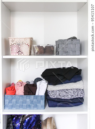 Different clothes in home wardrobe. Small space organization. Vertical storage. 95415107