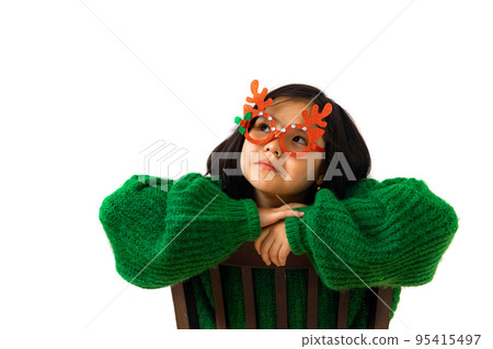 Cute asian child girl in green sweater and masquerade christmas glasses Cute asian child girl in green sweater and masquerade christmas glasses 95415497