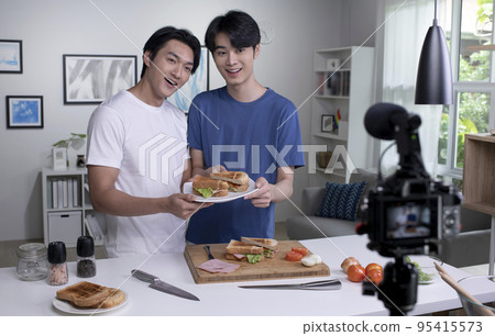 Asian male couple blogger influencer vlogger shooting video.LGBT gay couple live- streaming cooking Asian male couple blogger influencer vlogger shooting video.LGBT gay couple live- streaming cooking 95415573