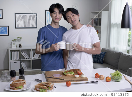 Asian gay couple cooking on kitchen. LGBT men couple are having fun together while preparing food Asian gay couple cooking on kitchen. LGBT men couple are having fun together while preparing food 95415575