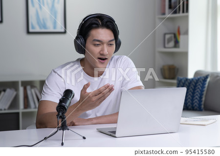 Asian business person, entrepreneur, speaker, office worker wearing headphones, looking at laptop Asian business person, entrepreneur, speaker, office worker wearing headphones, looking at laptop 95415580