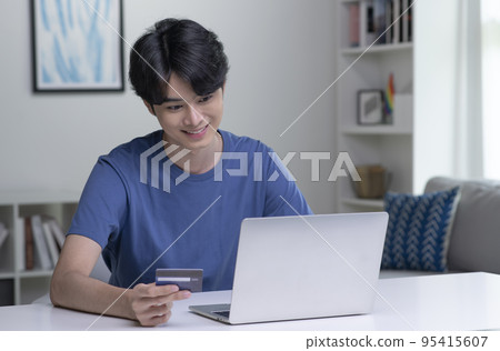 Asian man holding credit card and using laptop computer. Businessman working at home.Online shopping 95415607