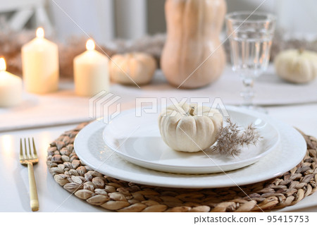 Thanksgiving day table setting with candles, fall decorations in modern kitchen. 95415753