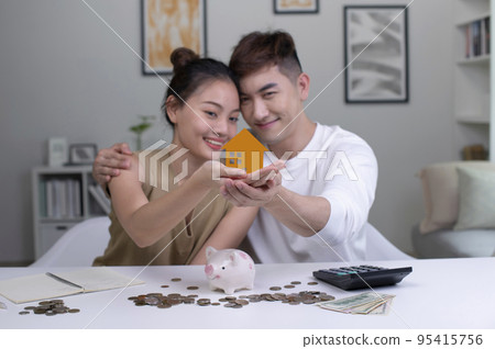Asian couples save money to buy a new house, save money for future security.Focus on toy house. 95415756