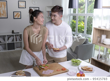 Asian couple is cooking on kitchen. Happy young couple are having fun together while prepare food Asian couple is cooking on kitchen. Happy young couple are having fun together while prepare food 95415783