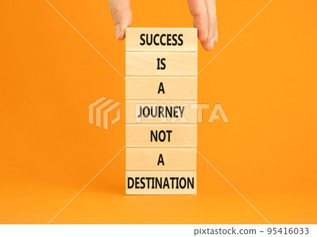 Success is a journey symbol. Concept words Success is a journey not a destination on wooden blocks on a beautiful orange background. Businessman hand. Business and success journey concept. Copy space Success is a journey symbol. Concept words Success is a journey not a destination on wooden blocks on a beautiful orange background. Businessman hand. Business and success journey concept. Copy space 95416033