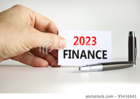 2023 Finance symbol. White paper with words 2023 Finance. Businessman hand. Metallic pen. Beautiful white table white background. Business and 2023 finance concept. Copy space. 95416041