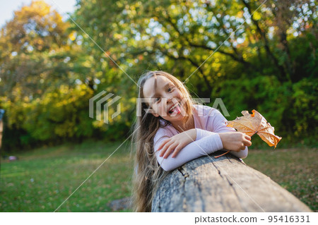 A cute little girl lies on a fallen log in the park. A cute little girl lies on a fallen log in the park. 95416331