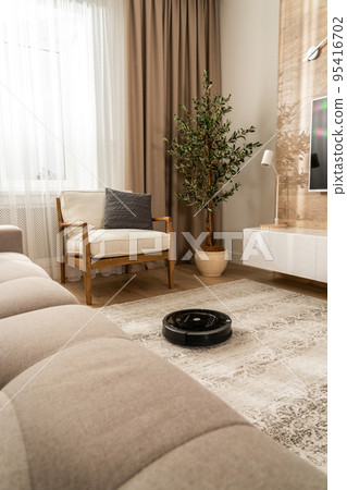 Homework of a round black vacuum cleaner robot in a modern apartment Homework of a round black vacuum cleaner robot in a modern apartment 95416702