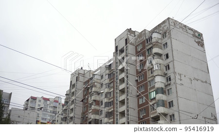 Large high soviet building panoramic view from bottom to top. An old dilapidated house from the times of the USSR. Concrete panel building against the background of gray clouds. Large high soviet building panoramic view from bottom to top. An old dilapidated house from the times of the USSR. Concrete panel building against the background of gray clouds. 95416919