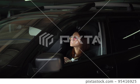 A business woman looks in a car mirror and straightens her hair. A young woman in glasses and a suit in a parking lot sits in a car and straightens her hair. A business woman looks in a car mirror and straightens her hair. A young woman in glasses and a suit in a parking lot sits in a car and straightens her hair. 95416925
