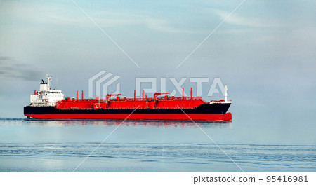 Long oil and gas petrochemical tanker offshore in opensea with 3 red tanks for liquefied gas, refinery industry cargo ship sails on the high seas under the sky with copy space, nobody. 95416981