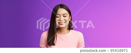 Cheerful tender lovely asian girl brunette, close eyes happily smiling, satisfied, receive good news, dream come true, stand purple background joyful, grinning from happiness and joy 95418971