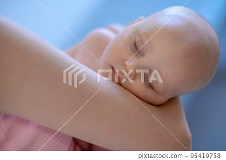 Caring female parent cradling her cute baby 95419758