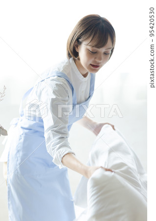 Cute woman making a bed Cute woman making a bed 95420530