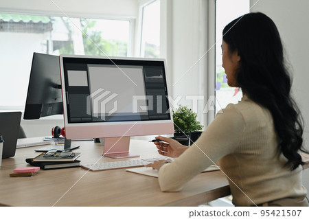 Rear view of female photo editors sitting in creative workplace and retouching photos on personal computer 95421507