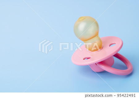 Orthodontic pacifier on a blue background. Pink baby pacifier Orthodontic pacifier on a blue background. Pink baby pacifier 95422491