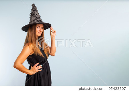 Happy brunette woman in halloween witch costume with black hat 95422507