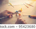 Children hands with Toy iron plane. Metal constructor with screwdrivers. Dream, play and create 95423680